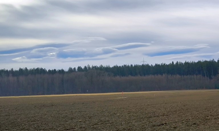 Föhnfische über einer Landschaft mit landwirtschaftlicher sowie forstwirtschaftlicher Nutzung.