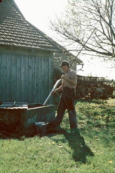 Bauer beim Schöpfen von Wasser aus dem Dachbrunnen 