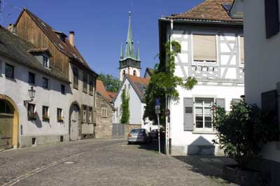 Die in der Tradition der mittelalterlichen Stadtstruktur stehende Durlacher Kelterstraße. Im Hintergrund der Turm der katholischen Pfarrkirche St. Peter und Paul. 